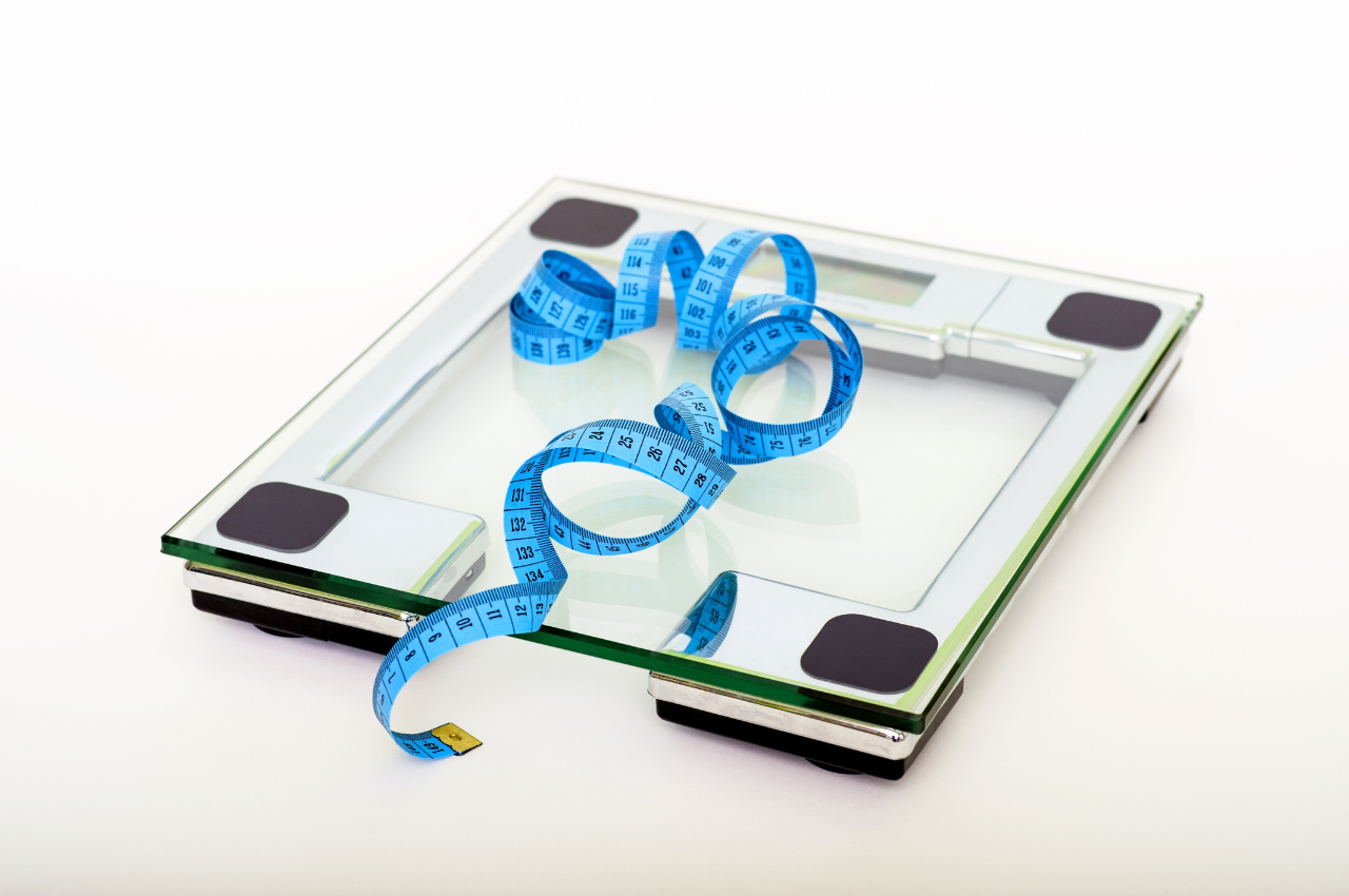 weight management scale and measuring band blue measuring band laying on top of a glass weight scale
